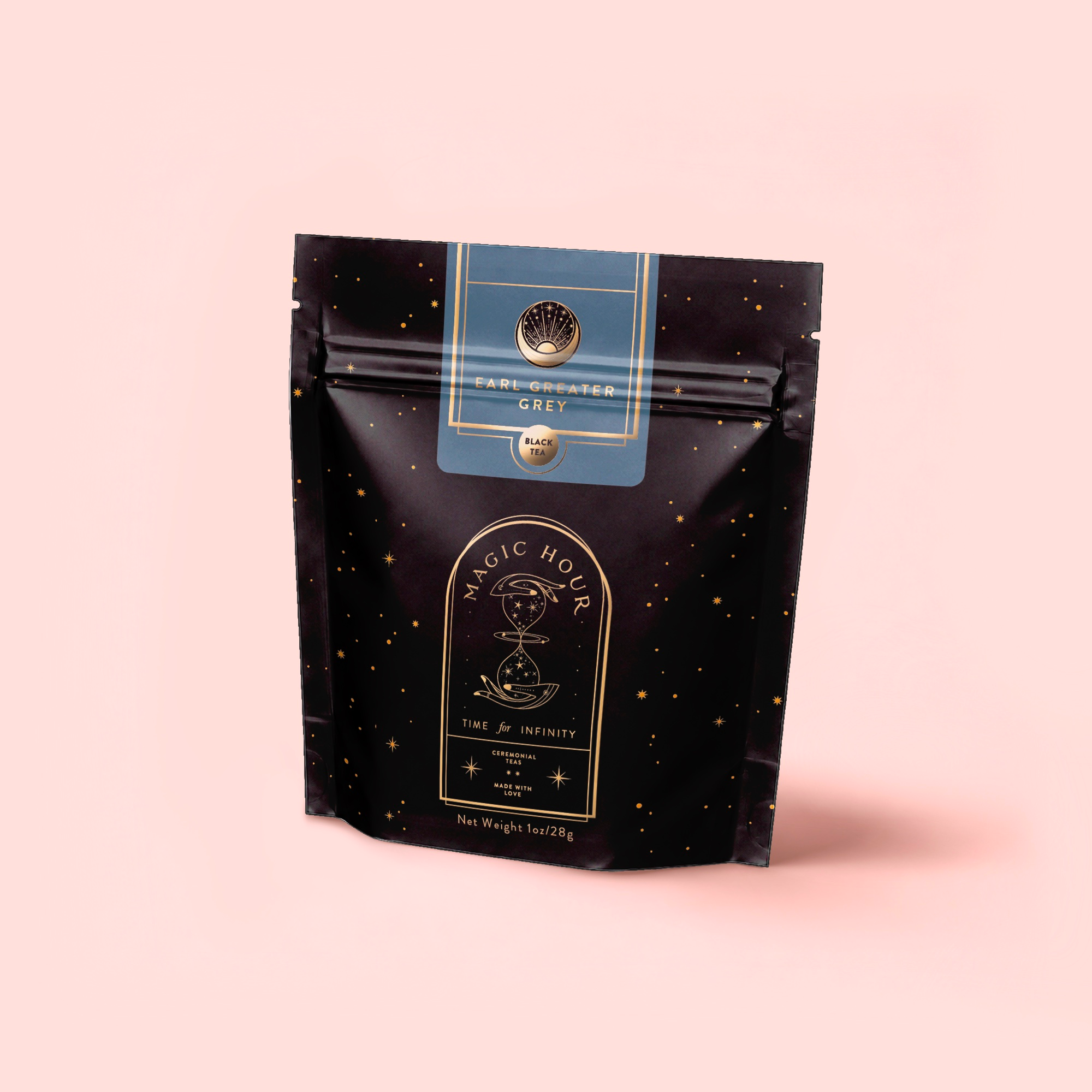 A black resealable pouch labeled "Earl Greater Grey: Tea for the Bright & Bold" contains organic Earl Grey tea, with gold stars and a celestial design on a light pink background.