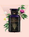 A dark purple tea jar labeled "EARTH Grounding & Manifestation Tea" rests amid green leaves and colorful flowers framed by a gold triangle—an inviting wellness blend featured in the Monthly Tea Subscription Box.