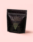 A black, resealable pouch labeled "Earth: Stabilizing and Nourishing Herbs, Roots, and Puerh Tea for Digestion & Grounding" from Magic Hour stands upright on a light pink background with gold accents and star designs.