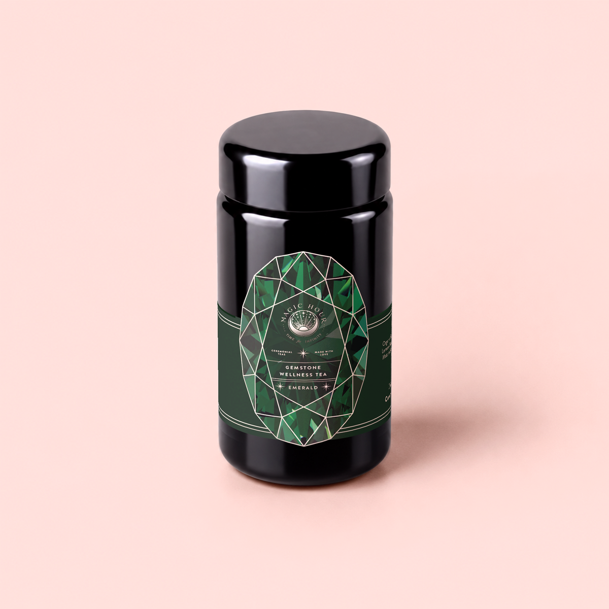 A black cylindrical container of Emerald - Cherry Blossom Pineapple Cream Green Tea, an organic Japanese green tea loose leaf wellness tea, featuring a green geometric label and set against a pale pink background.
