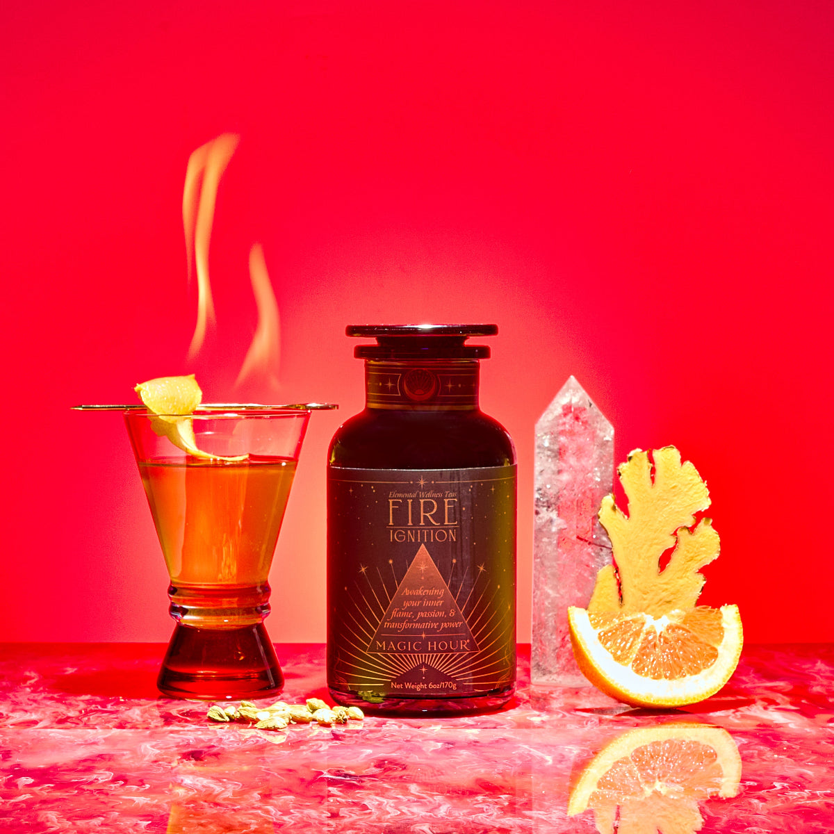 A cocktail with a lemon twist and flame sits beside a dark apothecary bottle labeled “Fire,” featuring crystal, ginger root, orange slice, and cardamom—showcasing adaptogens and metabolism-boosting herbs against a vibrant red backdrop.