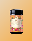 A jar of Flower Powder: Dragon Fruit Matcha features a vibrant floral label with dragon fruit art on a solid orange background and is made with organic ceremonial matcha.