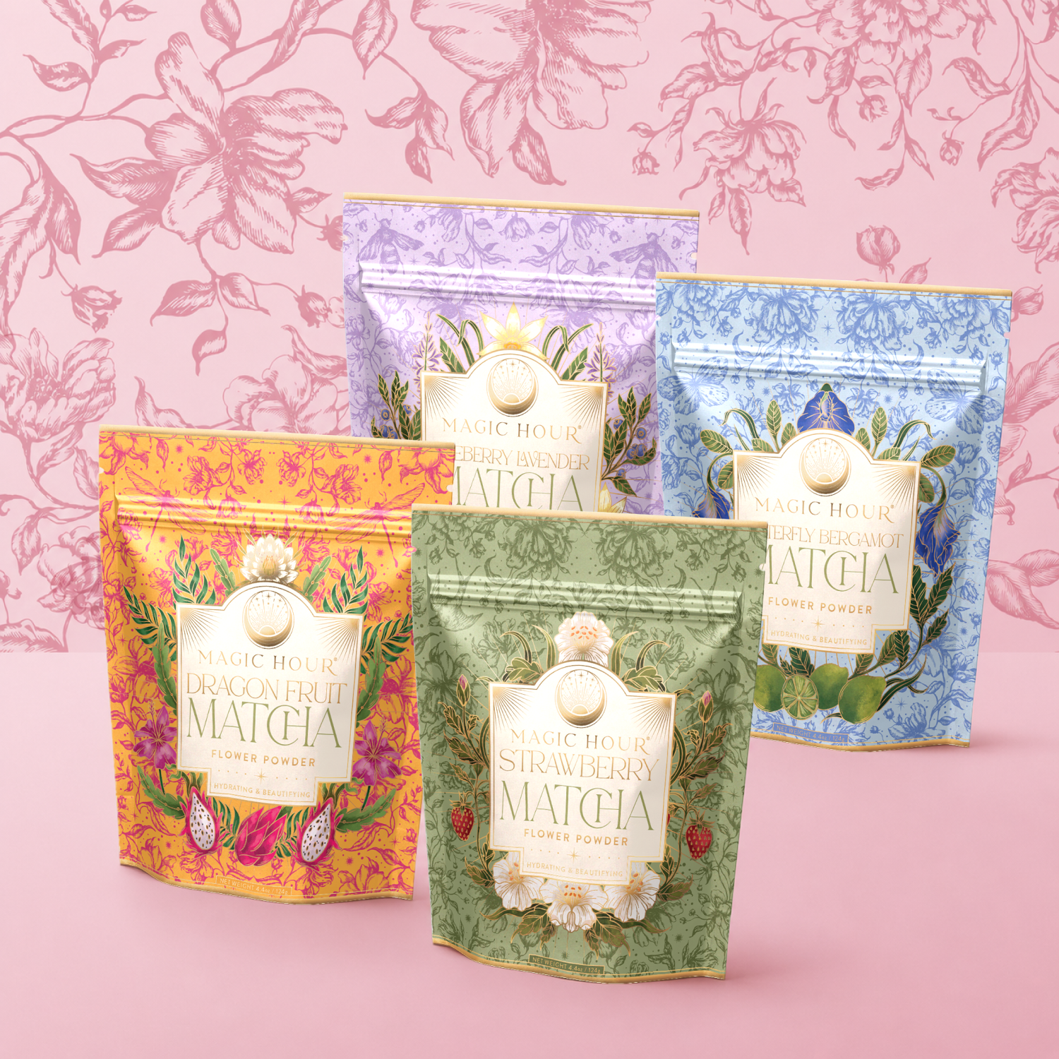 Four colorful pouches from the Flower Powder: Matcha Bundle are arranged in front of a pink floral wallpaper, each labeled with a different flavor—Dragon Fruit, Strawberry, Berry Lavender, and Berry Bergamot. Crafted with antioxidant-rich Kagoshima ceremonial matcha, these vibrant blends deliver both exquisite taste and wellness benefits in every cup.