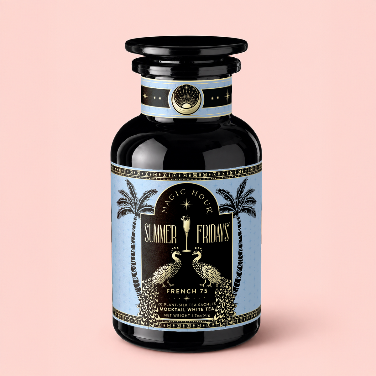 A black tea canister labeled “French 75: Lemon Sparkling Wine White Mocktail Tea for Cool, Calm Radiance,” adorned with gold accents, two peacocks, and palm trees, rests against a light pink background—an elegant tribute to wellness mocktail culture and aromatic French lavender.
