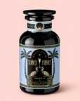 A black tea canister labeled “French 75: Lemon Sparkling Wine White Mocktail Tea for Cool, Calm Radiance,” adorned with gold accents, two peacocks, and palm trees, rests against a light pink background—an elegant tribute to wellness mocktail culture and aromatic French lavender.
