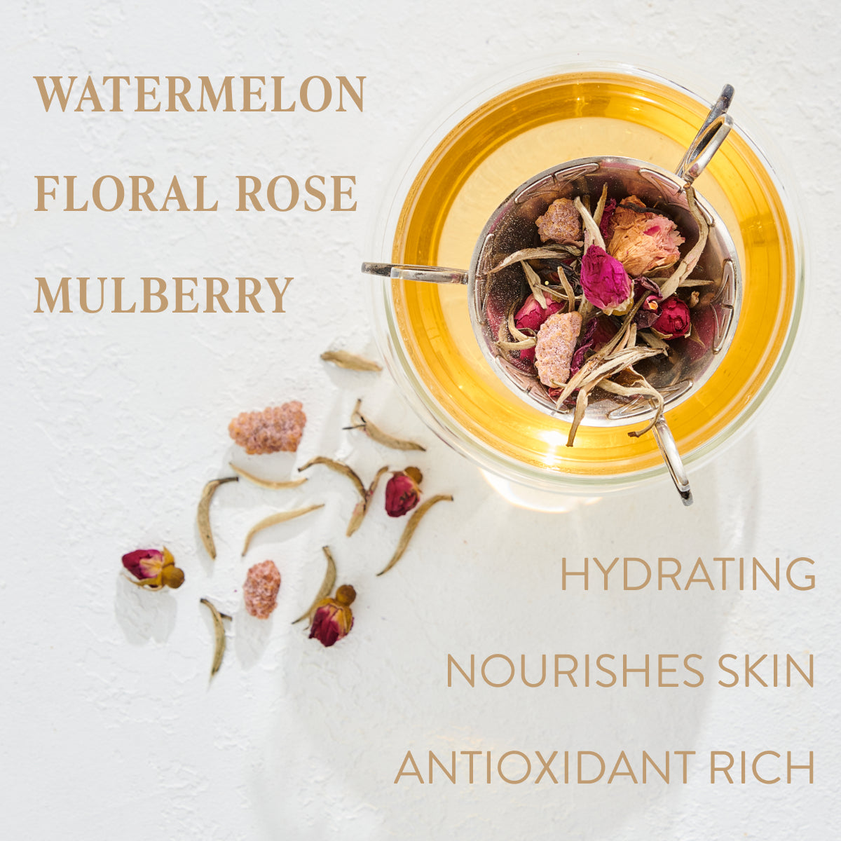 A cup of tea infused with various floral ingredients, including rose petals and dried mulberries, sits next to some scattered tea leaves and flowers. The words "WATERMELON, FLORAL ROSE, MULBERRY" and "HYDRATING, NOURISHES SKIN, ANTIOXIDANT RICH" are displayed around this organic loose leaf tea from Magic Hour called Gemini: Watermelon-Rose-Mulberry Pomegranate Tea for Beauty, Balance & Quenching Curiositeas.
