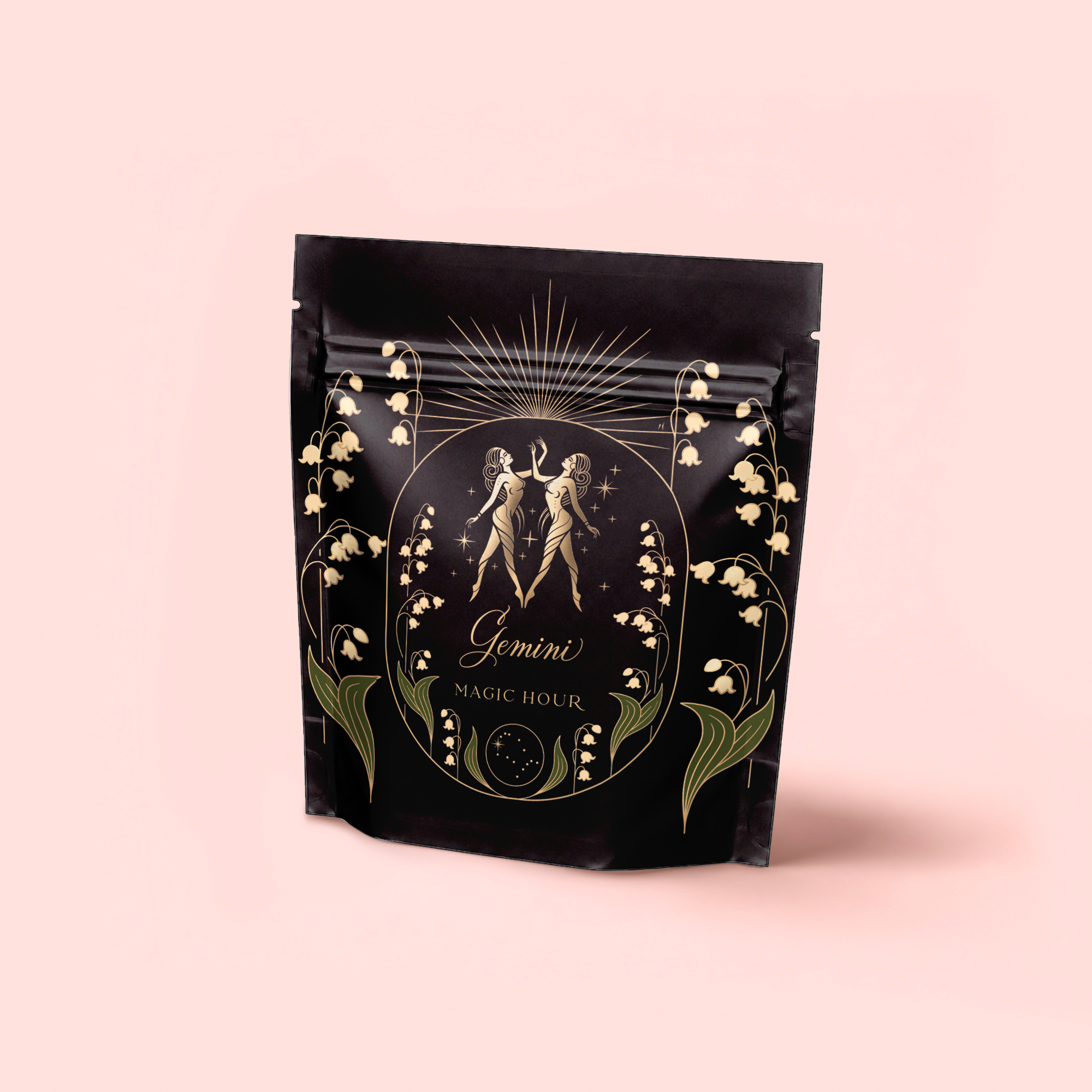 A black package with gold and green art, mirrored figures, "Gemini" text, florals, and a pink label that reads "Magic Hour," highlighting Gemini: Watermelon-Rose-Mulberry Pomegranate Tea for Beauty, Balance & Quenching Curiositeas.