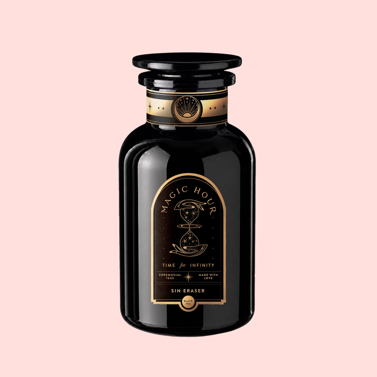 A black glass bottle with a gold and black label reading “Magic Hour” and “Time for Infinity,” featuring an hourglass illustration and the product name “Sin Eraser™ : Puerh Tea,” evokes the rich tradition of vintage Puerh. This striking piece stands out on a light pink background, blending timeless elegance with the essence of fine Puerh tea.