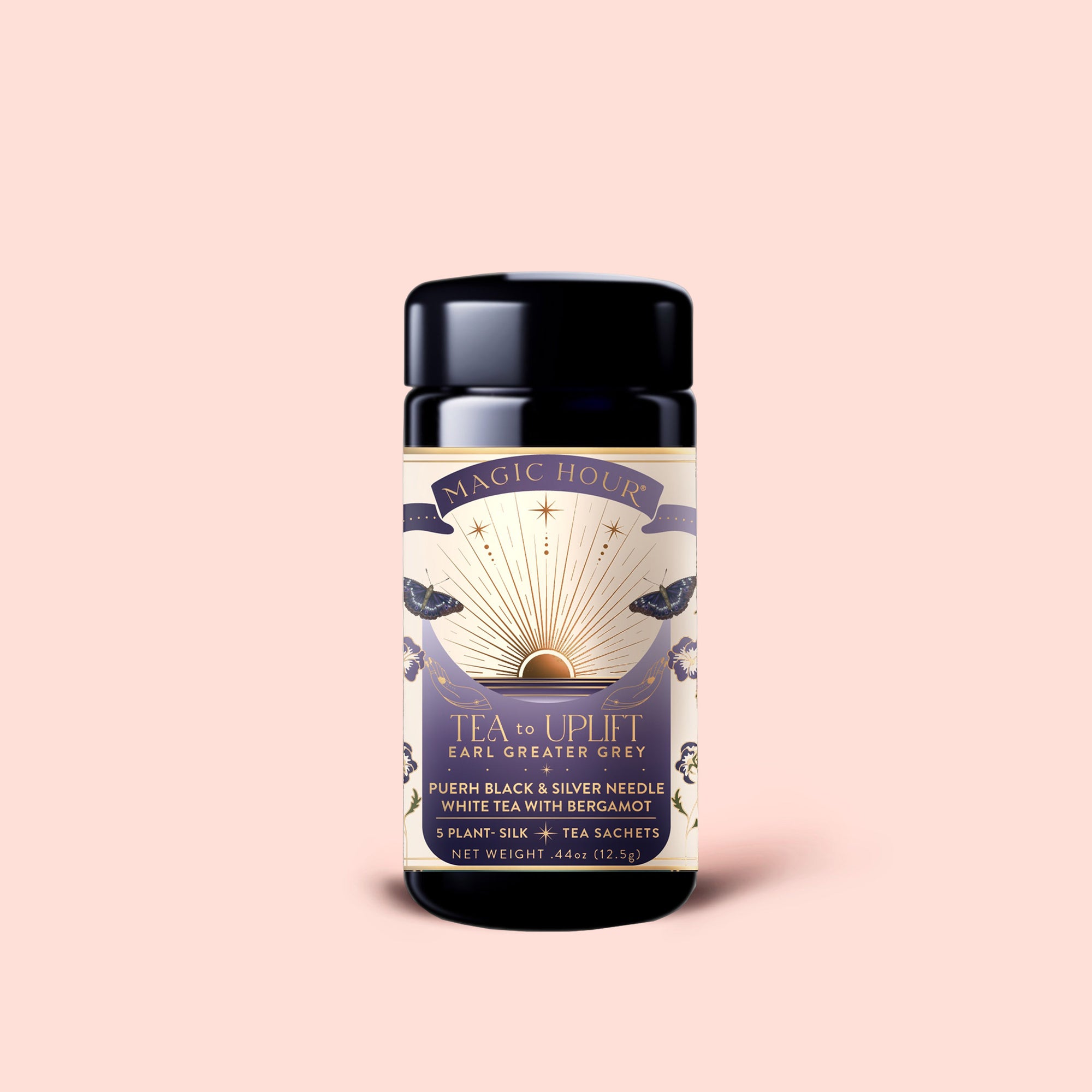 A cylindrical tea tin labeled "Tea to Uplift: Earl Greater Grey: Black &amp; White Tea with Bergamot" is adorned with sun rays, a golden sun, and elegant botanical designs. The tin holds organic Earl Grey tea sachets infused with uplifting bergamot. Set against a pale pink background, this blend promises both beauty and flavor.