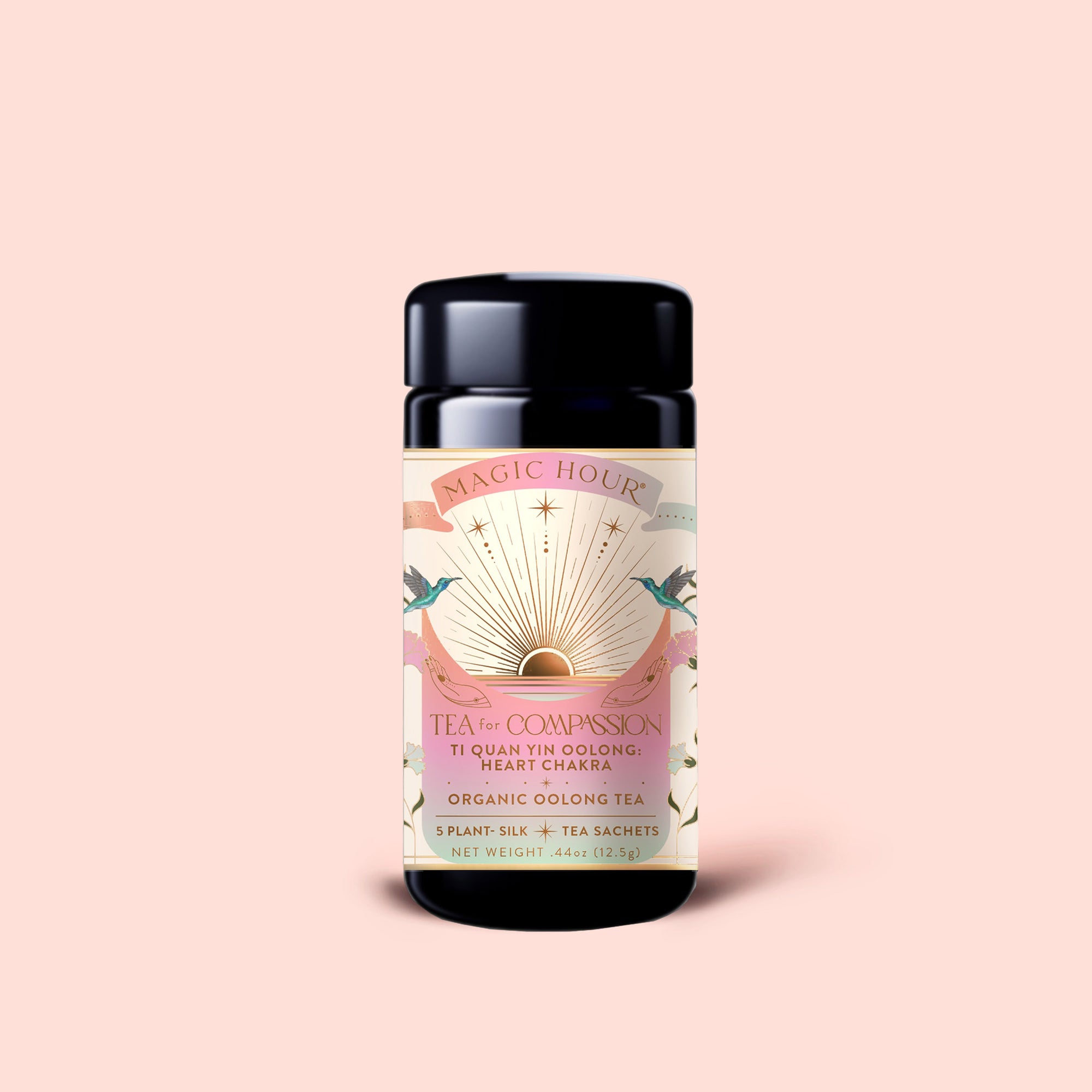 A jar of Magic Hour’s Tea for Compassion: Ti Quan Yin, adorned with a sunburst design and pastel hues, features illustrations of hands and plants. The label notes it’s an organic Oolong tea with 5 sachets, crafted in the traditional Ti Quan Yin style for a mindful sipping experience.