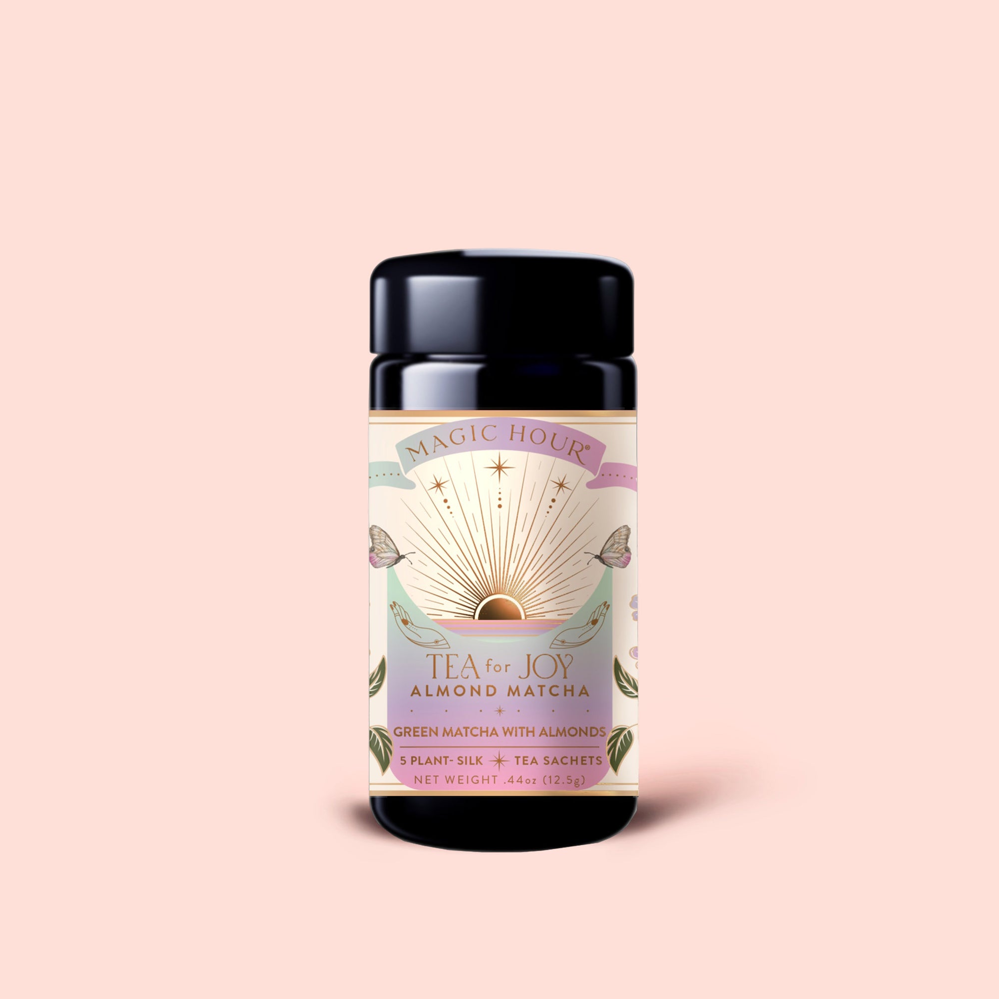 A container of Tea for Joy: Almond Matcha: Green Matcha Tea with Almonds, an antioxidant-rich matcha blend featuring a sunburst design label, set against a light pink background.