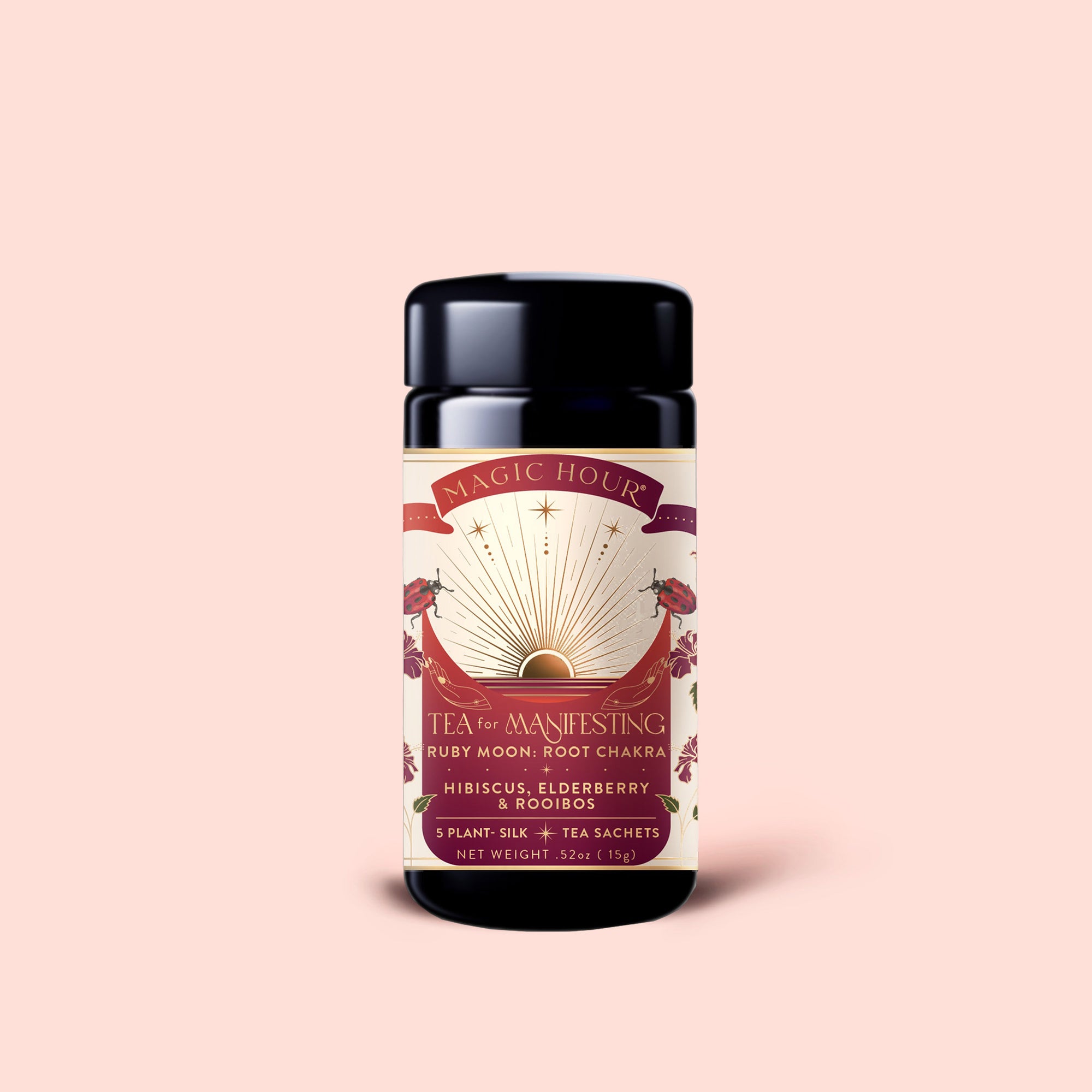 A container of Magic Hour "Tea for Manifesting: Ruby Moon" herbal tea, featuring hibiscus, elderberry, and passionfruit, adorned with sunburst celestial artwork and pink floral details on a light pink background.