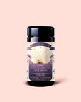 A jar of Tea for Comfort: Lucid Dreams: Turmeric-Tulsi Chai Tea—a soothing, caffeine-free blend crafted with care. The label features a sun, palm trees, and a purple and gold design on a pale pink background, perfectly reflecting the essence of this calming Tulsi turmeric herbal tea for sleep.