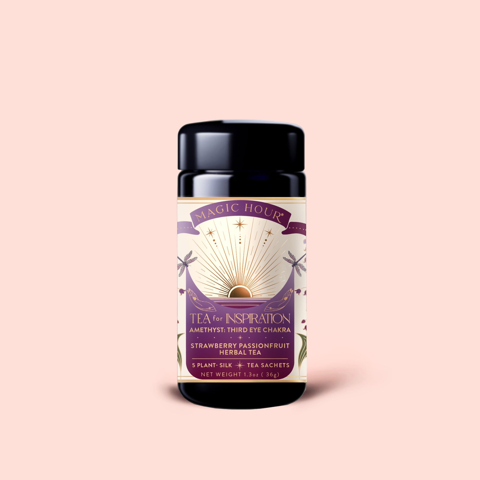 A black tea canister labeled "Tea for Inspiration: Amethyst: Strawberry Passion Fruit Herbal Tea Blend," featuring the third eye chakra and organic herbal ingredients designed to enhance spiritual clarity, is set against a light pink background.