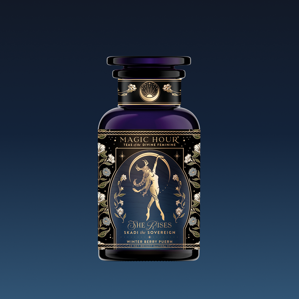 A dark, ornate glass jar labeled "Skadi The Sovereign - Winter Berry Puerh" features gold floral patterns and a woman with antlers. This ceremonial tea blend offers winter resilience with berry-infused puerh.