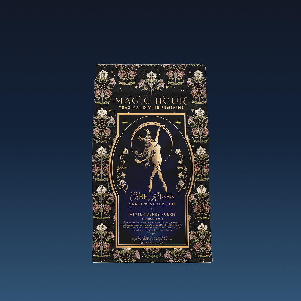 A decorative black and gold tea package labeled "Skadi The Sovereign - Winter Berry Puerh" features a woman with antlers, floral patterns, and the text "She Rises" and "Winter Resilience Berry-Infused Pu-erh Tea.