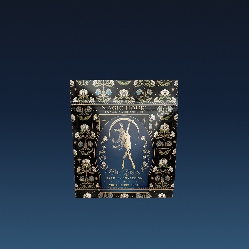 The "Skadi The Sovereign - Winter Berry Puerh" comes in a black and gold floral tea package with an illustration of a woman with a bow. This berry-infused puerh blend is inspired by winter resilience.