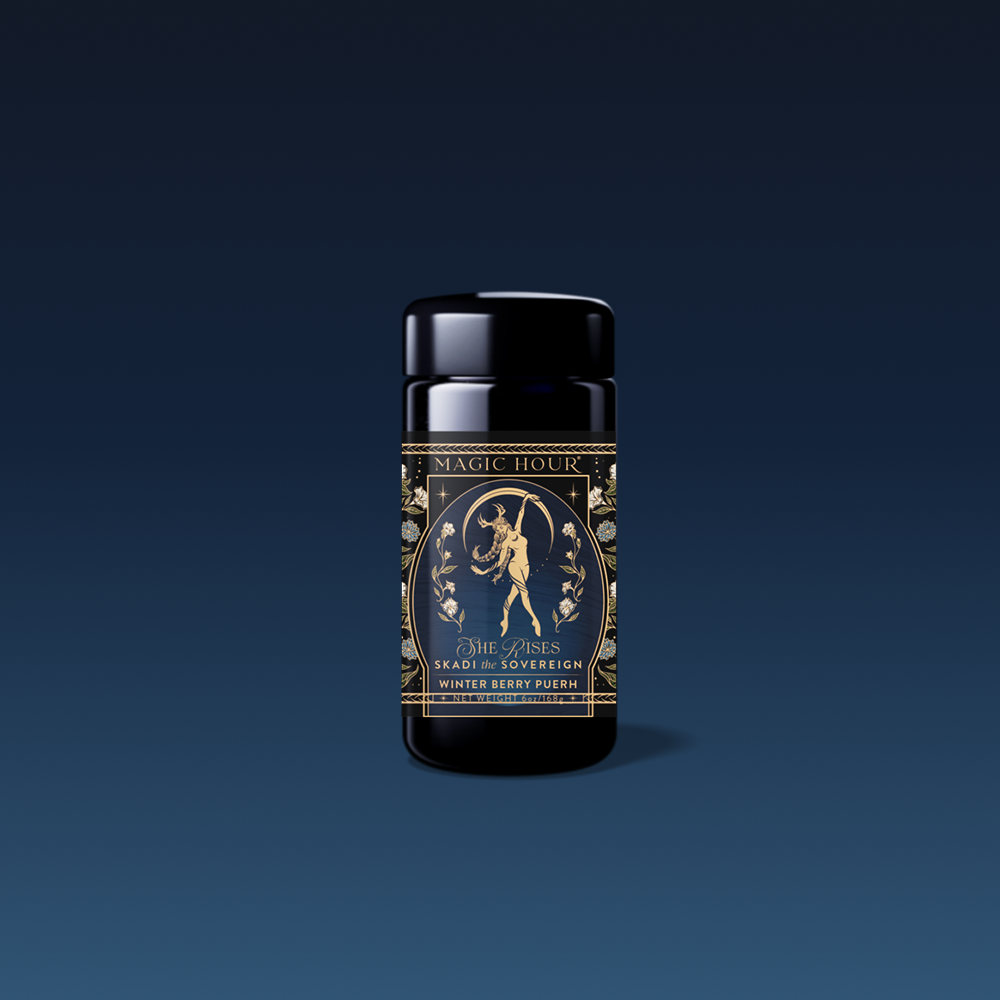 A dark blue and gold tea canister labeled "Magic Hour" features an ornate design with a figure holding a crescent moon, reading “Skadi The Sovereign - Winter Berry Puerh”—a ceremonial blend celebrating winter resilience. Background: gradient blue.