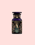 A dark glass bottle of “Persephone’s Potion: Pomegranate & Jasmine Green Tea” features ornate floral designs and an illustration of a woman holding a rose on the label, set against a pale pink background.