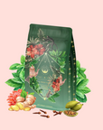 Moonlight in Marrakesh: Spiced Mint Green Tea packaging features floral and botanical designs, surrounded by illustrated leaves, hibiscus, ginger, pomelo, cardamom, and cloves on a light pink background.