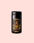 A black container labeled “The Sun: Energizing Adaptogenic Herbal Tea with Yaupon, Moringa & Turmeric” shows an illustrated woman in a dress, sunflowers, and "THE SUN" text, set against a light pink background.