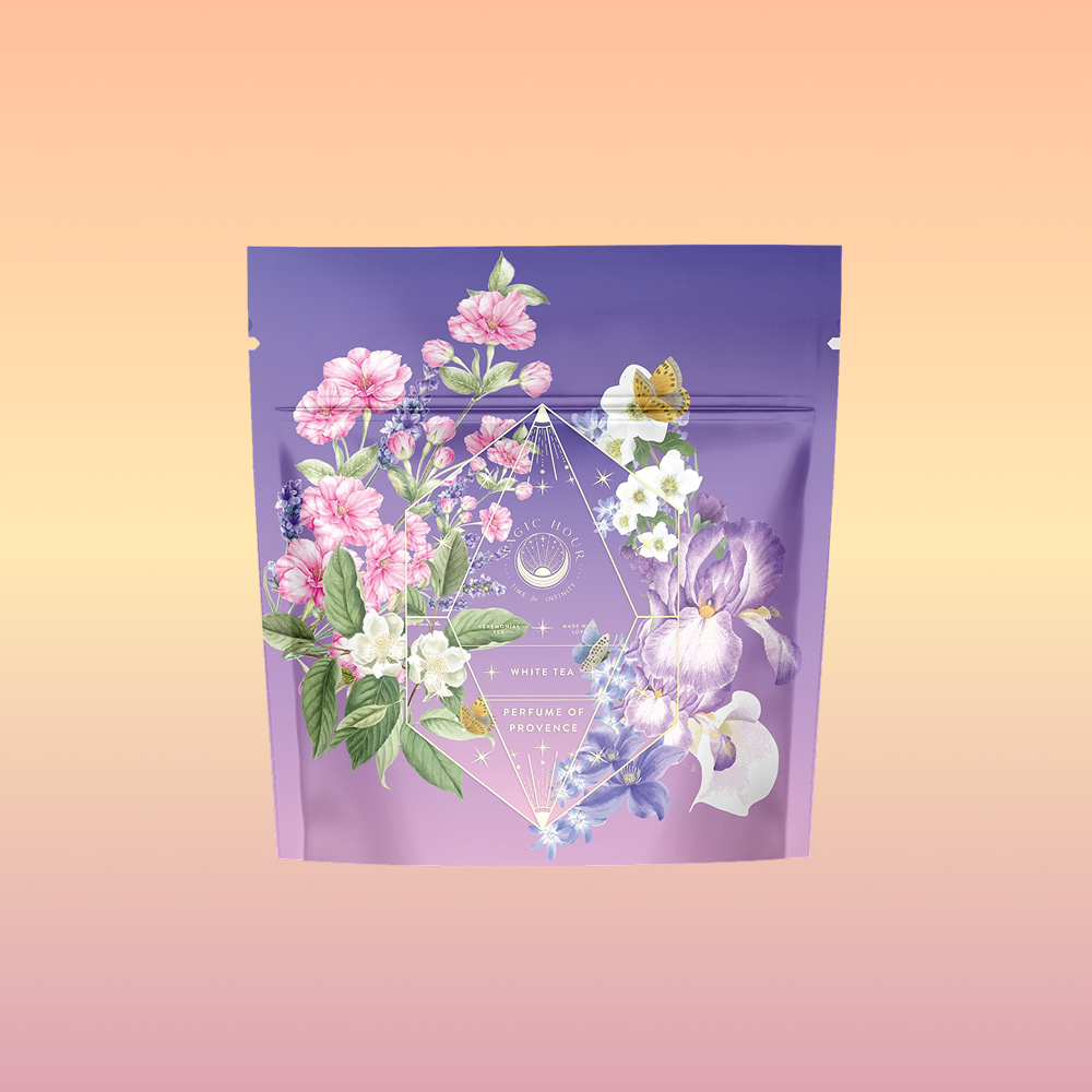 The Perfumes of Provence: Lavender Bouquet Tea for Calm Moods and Beautiful Skin features a lavender-toned pouch with pink, white blossoms, purple irises, and a butterfly on a peach-pink gradient background.