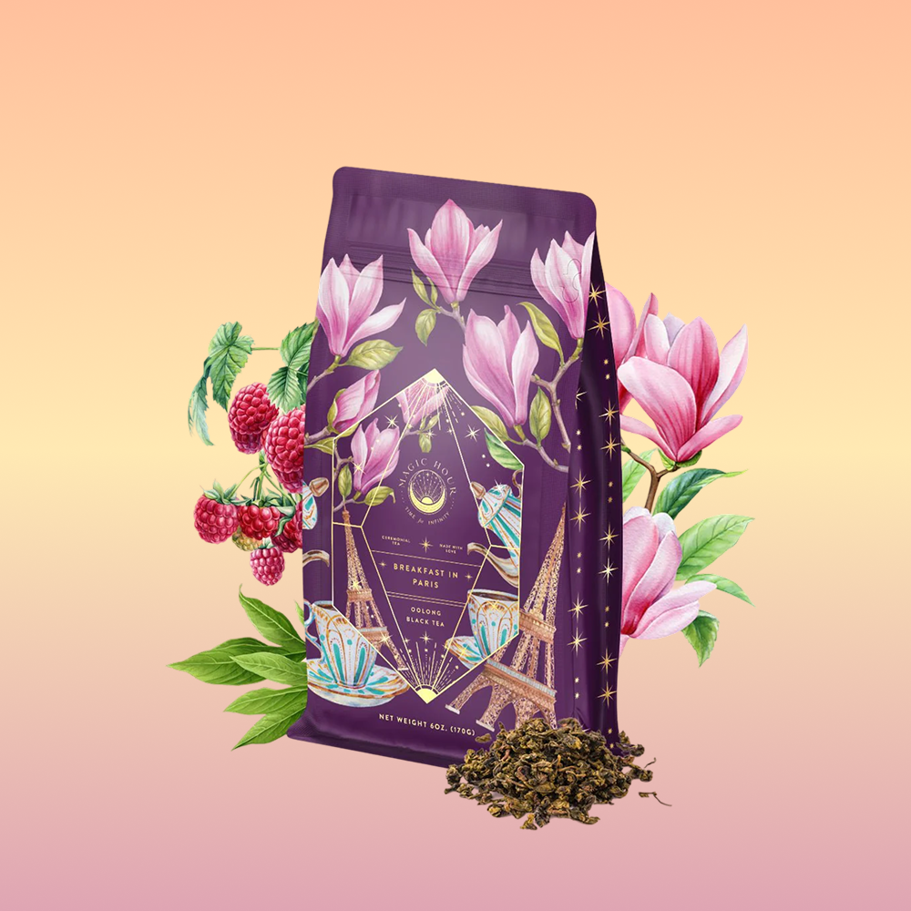 Breakfast in Paris-Oolong Black Tea Scented with Fruits & Flowers of Secret Parisian Gardens comes in a purple tea bag adorned with magnolias, raspberries, and the Eiffel Tower, set against a peach gradient background.