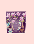 A purple package decorated with magnolia flowers, a tea set, and the Eiffel Tower highlights Breakfast in Paris-Oolong Black Tea Scented with Fruits & Flowers of Secret Parisian Gardens against a light pink background.