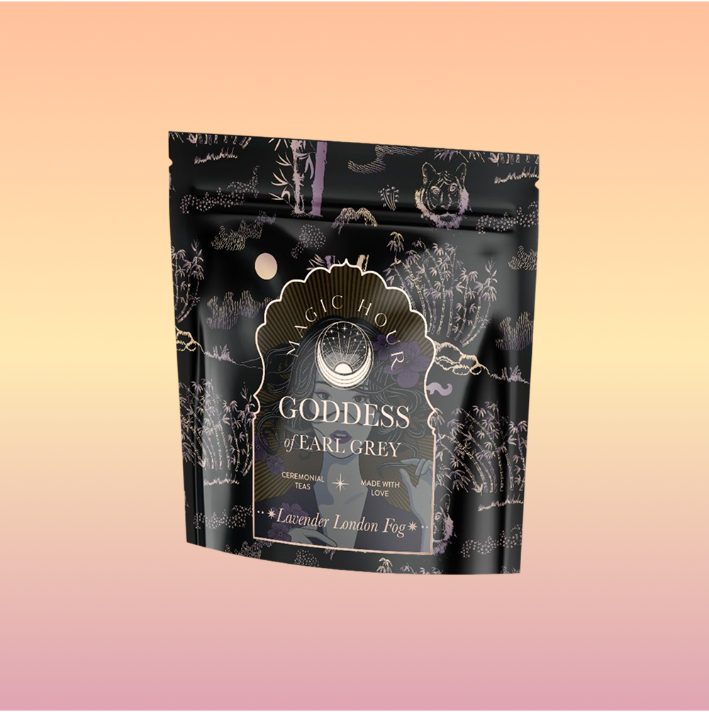 A stand-up pouch of "Goddess of Earl: Lavender London Fog- Tea for Blooming Clarity & Calm Moods" is shown against a soft pastel gradient background, with black packaging adorned with delicate lavender and botanical illustrations.