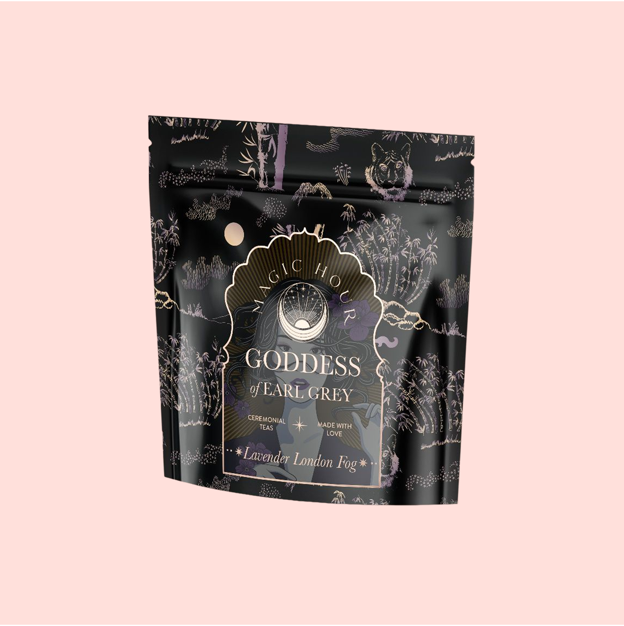 A black and purple resealable tea pouch labeled "Goddess of Earl: Lavender London Fog—Tea for Blooming Clarity & Calm Moods" features celestial illustrations and bergamot notes, displayed on a pale pink background.