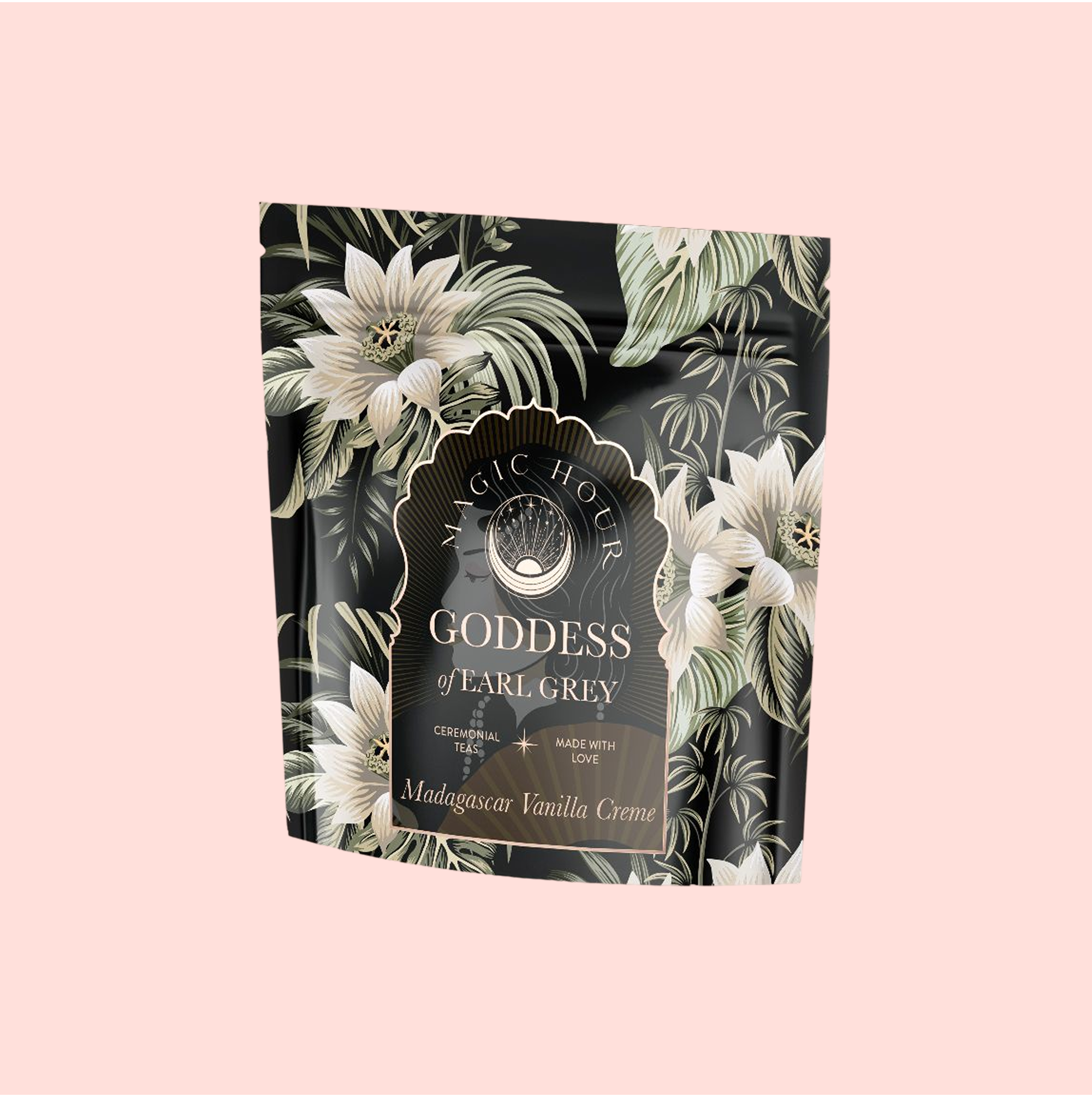 A stand-up pouch of Goddess of Earl: Madagascar Vanilla Creme Tea for Soothing Delight & Delicious Decadence features a dark floral design with white flowers, green leaves, and a light pink label. This blend includes organic black tea and bergamot vanilla.