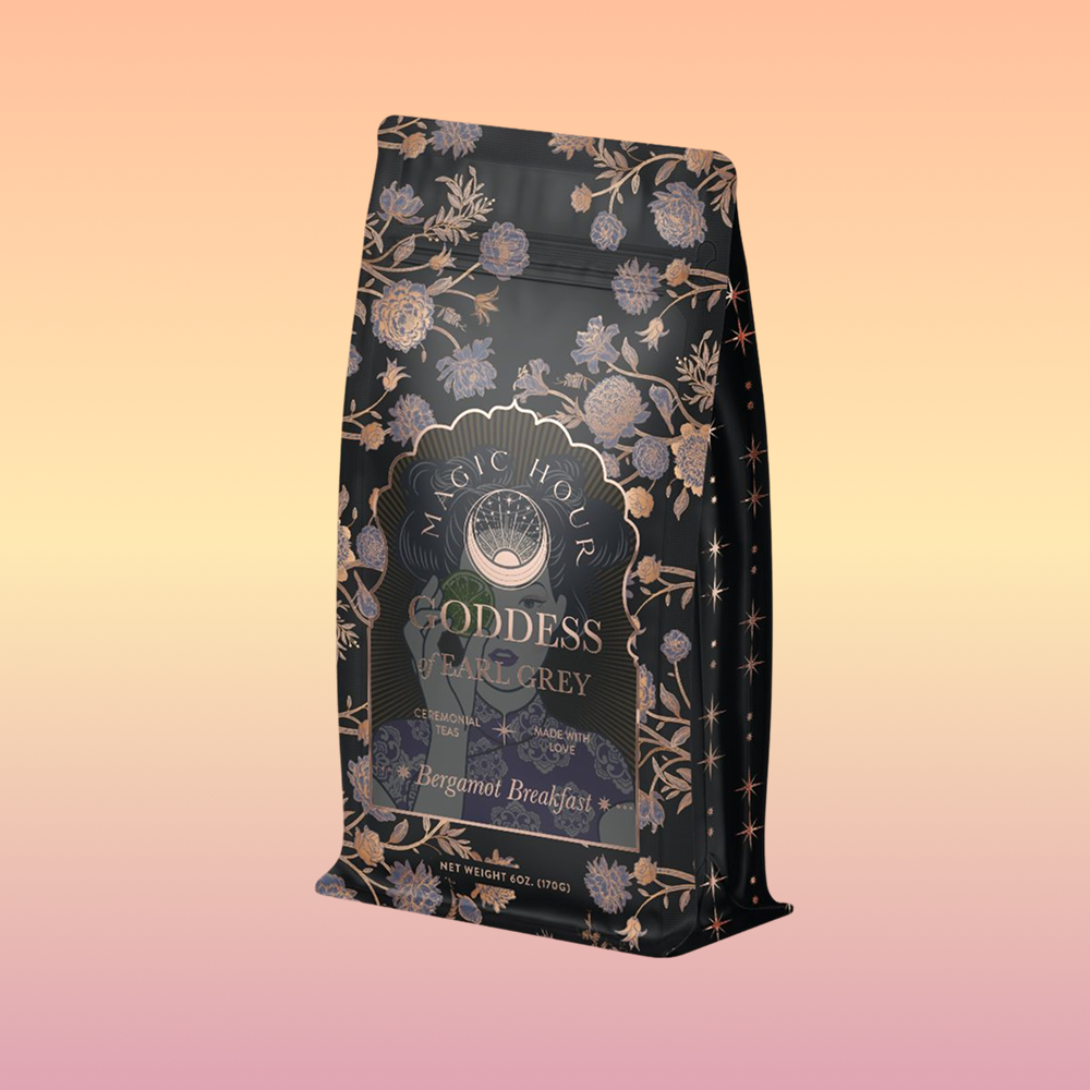 A decorative black bag of Goddess of Earl: Lady Luck Oriental Beauty Oolong Tea, featuring elegant gold and lavender floral designs, is displayed against a soft pastel gradient background.
