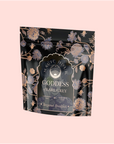 A black and gold floral pouch labeled "Goddess of Earl: Lady Luck Oriental Beauty Oolong Tea," adorned with ornate flower designs, sits on a pale pink background, highlighting this unique bergamot oolong blend.