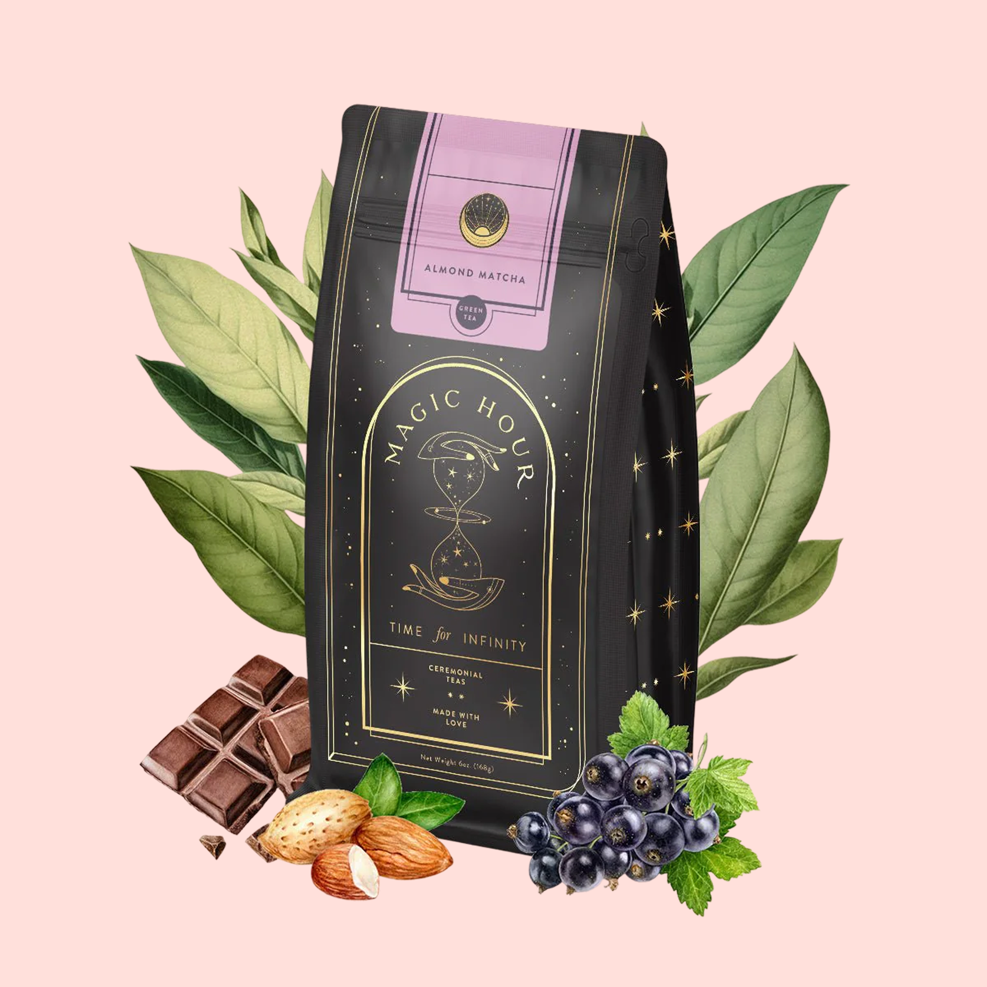 A black bag of Almond Matcha Green Tea for Joy with gold stars and an hourglass design sits on a light pink background, surrounded by green leaves, chocolate pieces, almonds, blackcurrants, and mint.