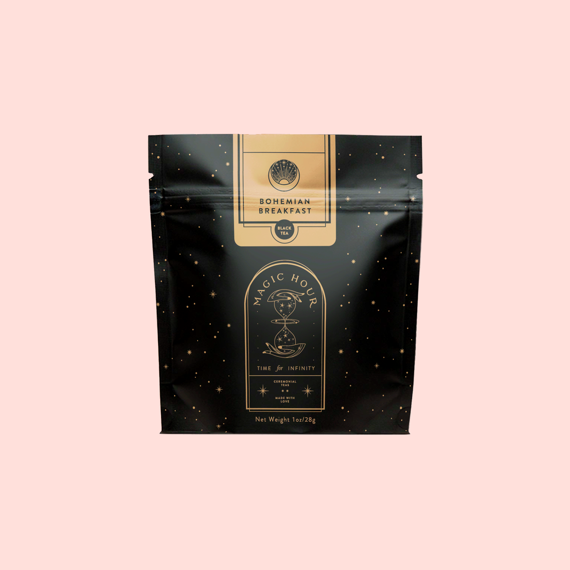 A black resealable pouch labeled "Magic Hour" and "Bohemian Breakfast Vanilla Puerh Black Tea for Digestion & Energy," with mystical designs and gold accents, stands against a pale pink background. This organic blend is a luxurious coffee alternative.