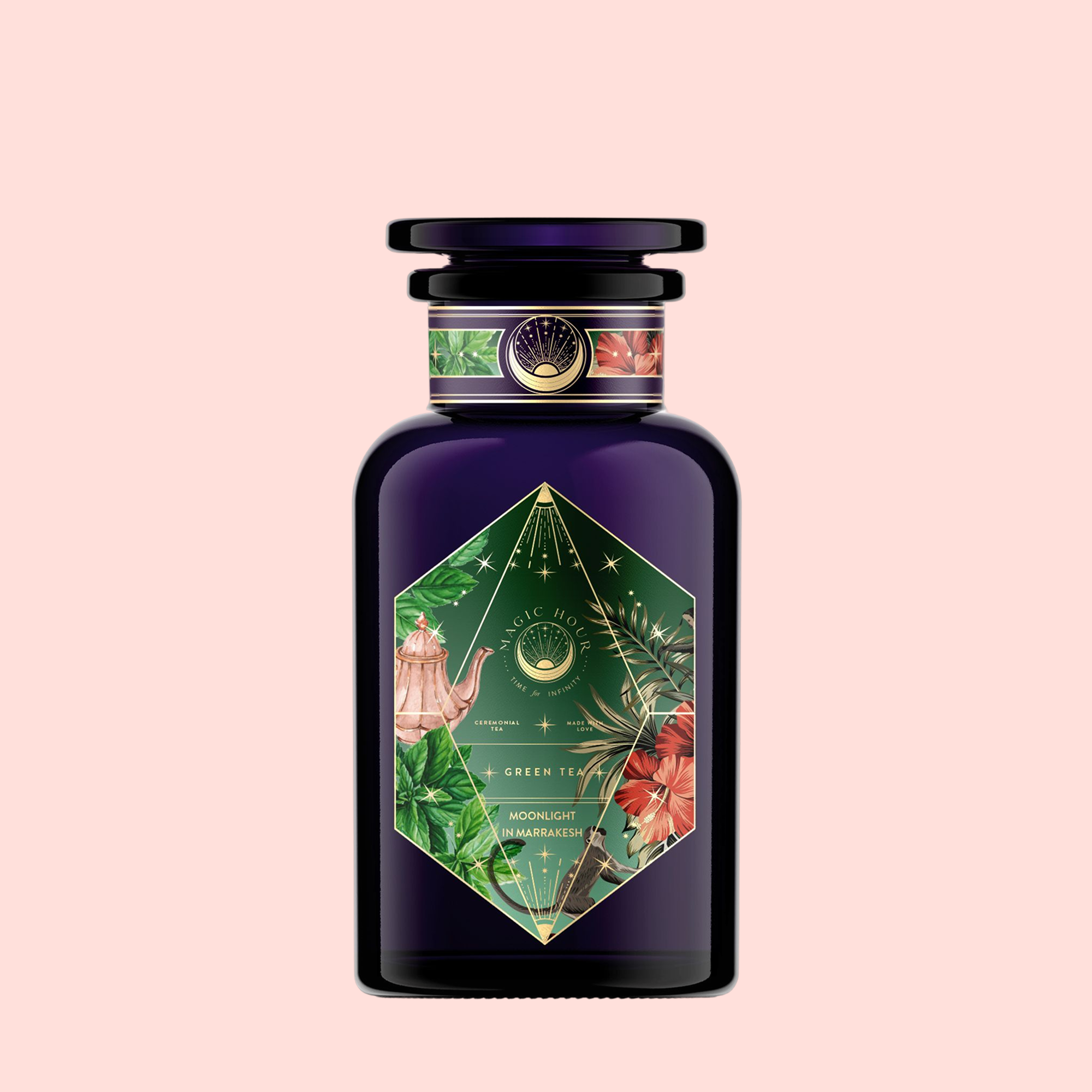 A dark purple perfume bottle with a hexagonal floral label of green leaves and pink flowers sits on a pale pink background. The label reads "Moonlight in Marrakesh: Spiced Mint Green Tea.