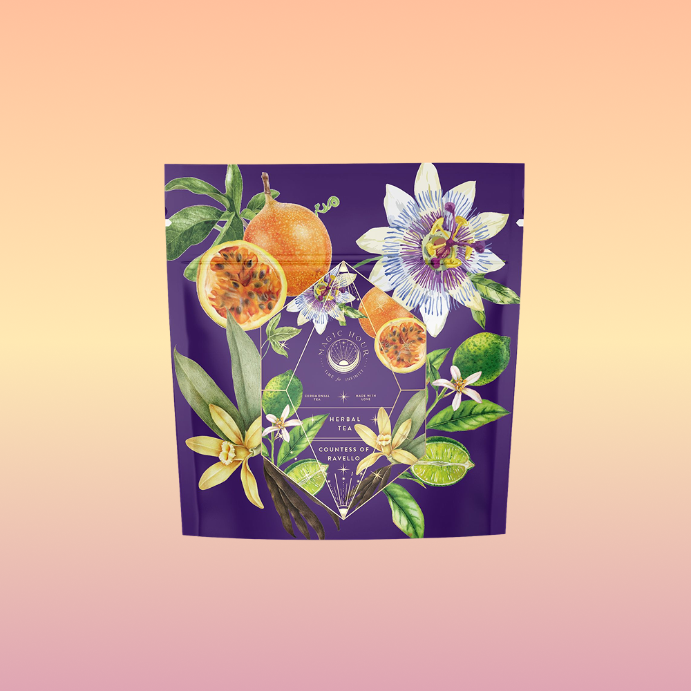 A purple tea package adorned with passionfruit, flowers, and green leaves on a peach-pink gradient showcases Romance in Ravello - Chocolate-Passionfruit-Rose-Cream White Tea.
