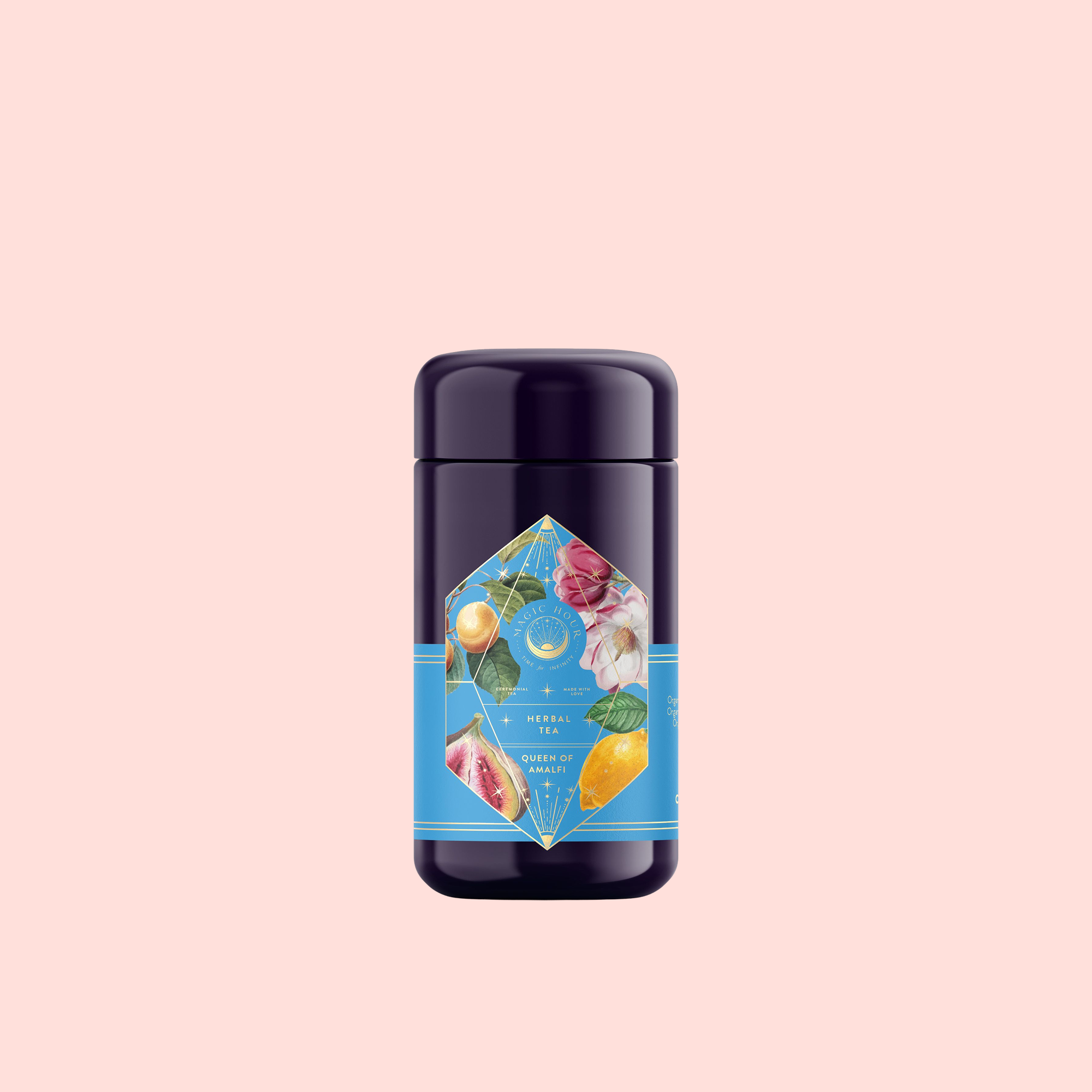 A dark purple cylindrical container with a bright blue label showing fruits and flowers sits on a light pink background, highlighting Summer in Amalfi—a refreshing blend of Organic Lemon Peel and Green Tea Oolong Mediterranean tea.