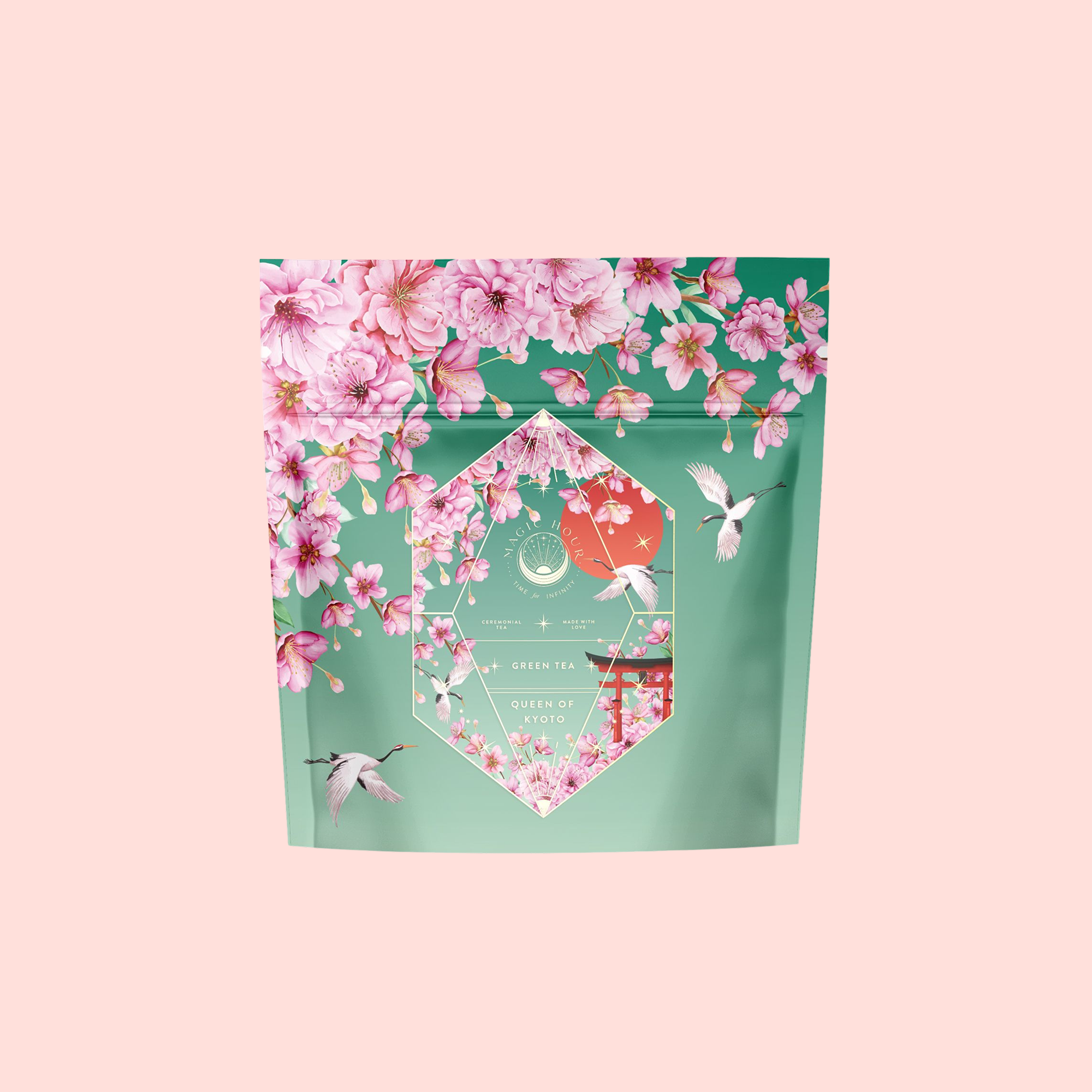 A Sencha Green Tea package called "Queen of Kyoto," decorated with pink cherry blossoms and hummingbirds on a teal background, set against a light pink backdrop—evoking the Japanese Cherry Blossom Festival.