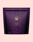 A purple Magic Hour pouch labeled "Sri Lankan Sunrise," featuring gold stars and text, stands against a pale pink background, evoking the vibrant taste of Sri Lankan breakfast tea within.
