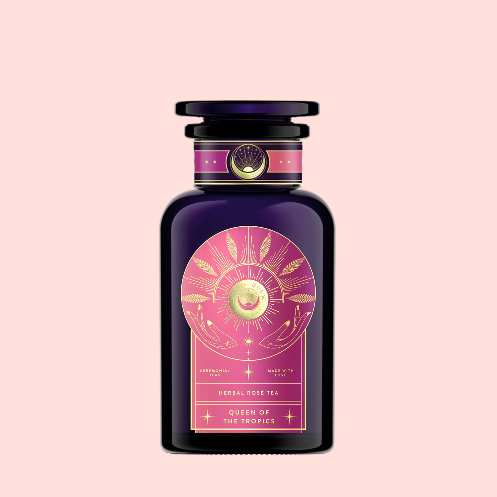 A dark purple glass bottle with a decorative label showing a golden sun, leaves, and pink accents. Labeled “Queen of the Tropics: Rosé all Day Alternative Tea,” it features Garcinia Cambogia and tropical fruits as a non-alcoholic rosé option. Light pink background.
