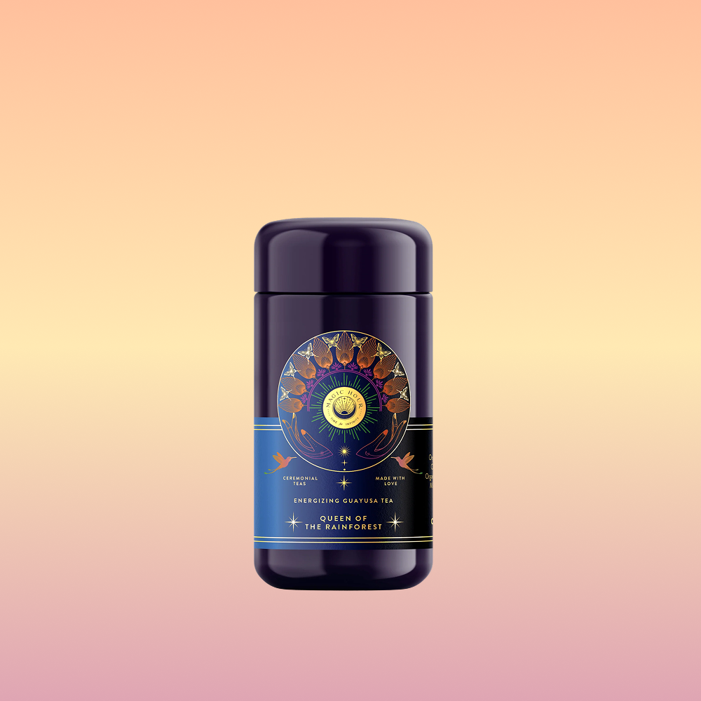 A dark blue tea canister labeled "Queen of the Rainforest : Cacao-Berry Tea" with celestial and botanical designs stands centered on a pink and yellow gradient background.