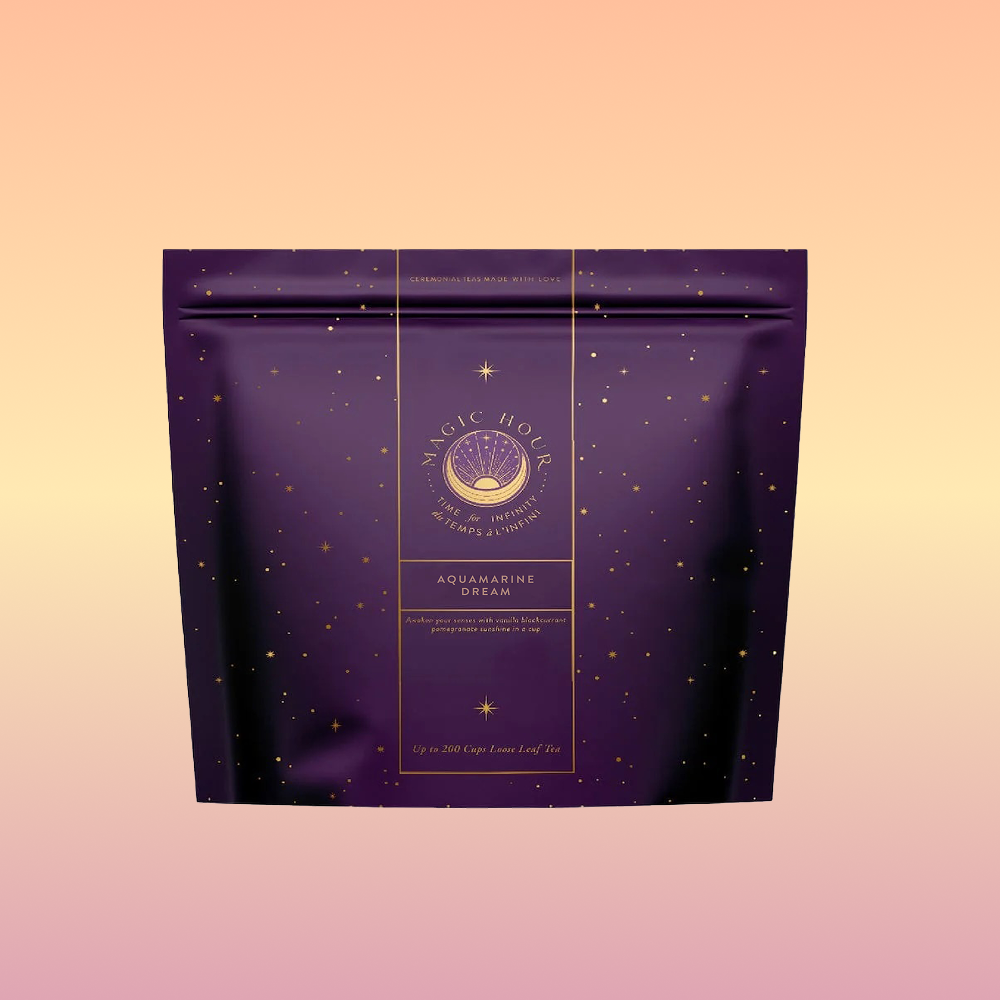 A purple "Aquamarine Dream - Soothing Herbal Ayurvedic Adrenal Tonic" tea bag features gold celestial designs and text on a pink-orange gradient background—the ideal calming sleep tea.