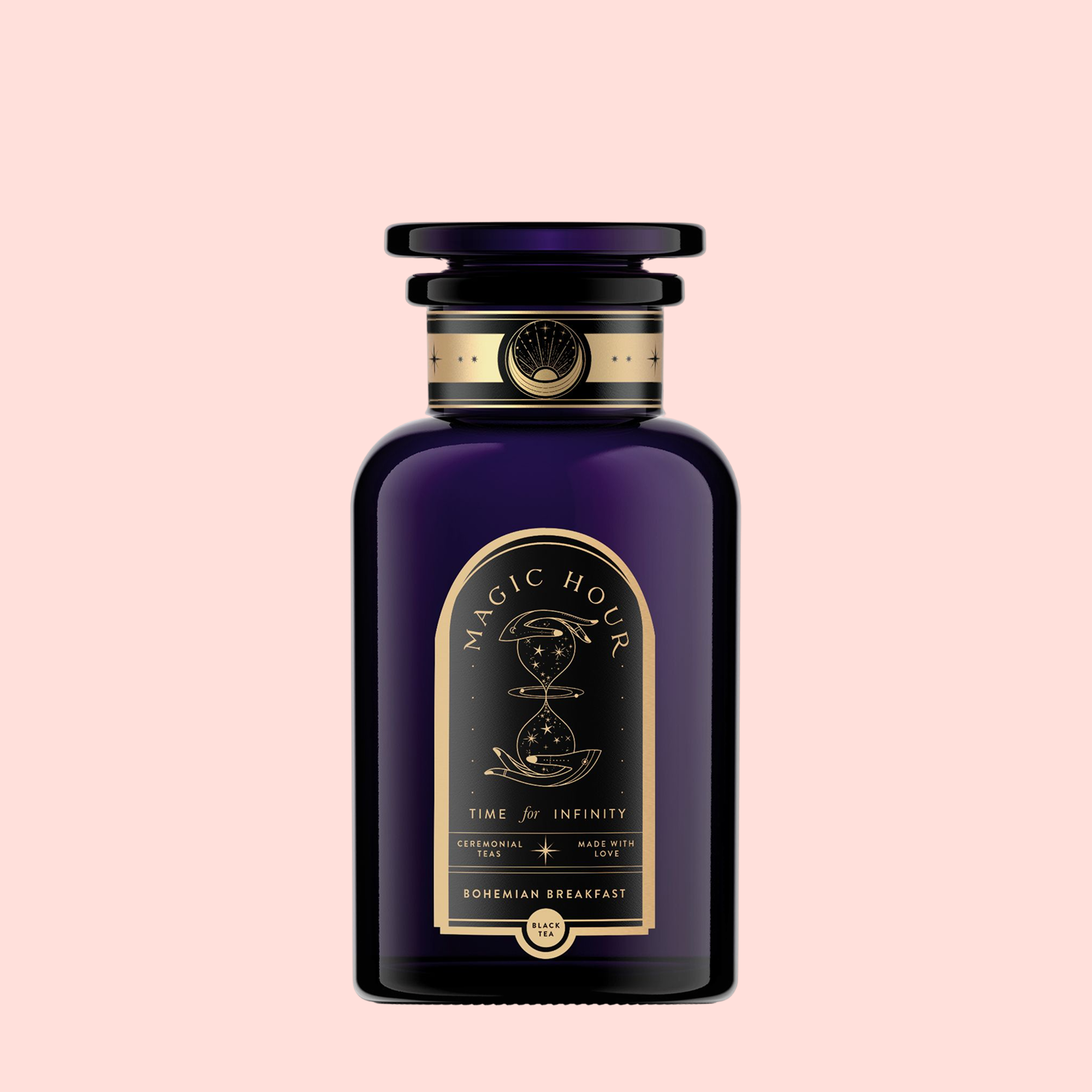 A dark purple glass bottle with black and gold label reads "Magic Hour" and "Bohemian Breakfast Vanilla Puerh Black Tea for Digestion &amp; Energy," featuring an hourglass illustration, displayed on a plain light pink background as a coffee alternative.