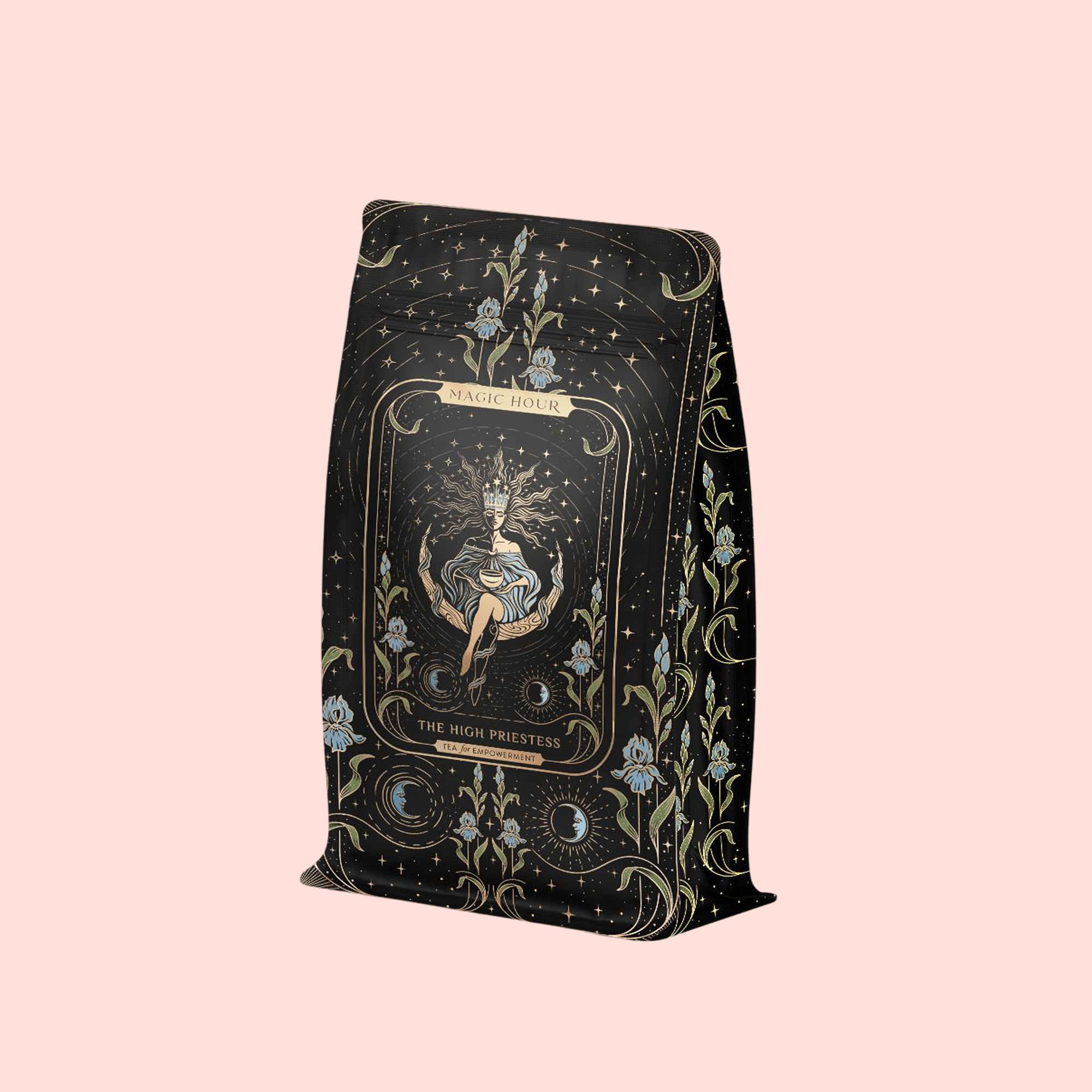 A decorative black tea bag with gold and blue floral designs and a mystical figure, labeled "The High Priestess Ginger-Mint-Cardamom Tea—Powerful Dreams &amp; Illuminated Insights" on a pale pink background.