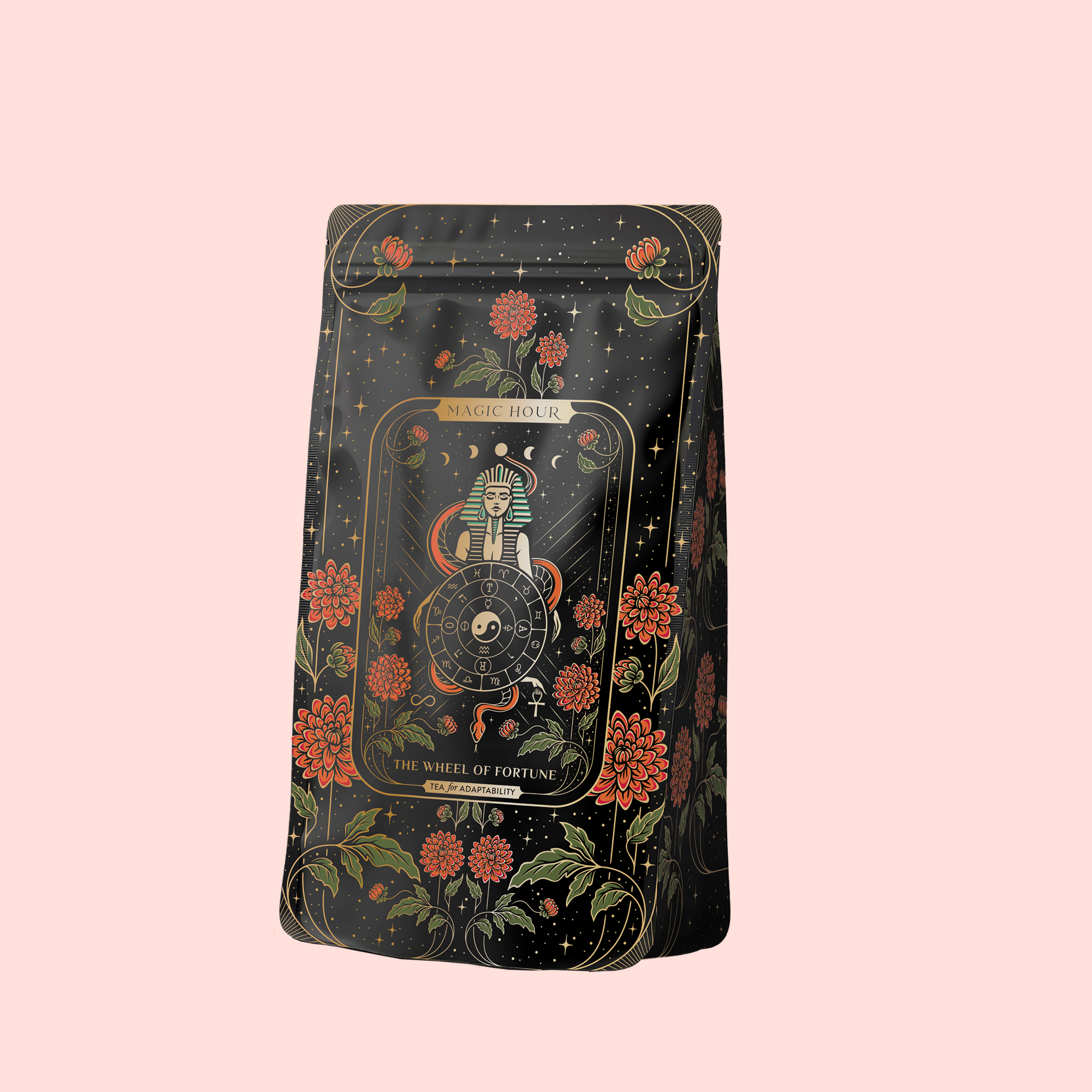 A black tea bag package with gold and red floral designs and a "The Wheel of Fortune" tarot card illustration showcases The Wheel of Fortune: Ginseng Spice Tea for Adapting to Change, an adaptogenic blend, set against a pale pink background.