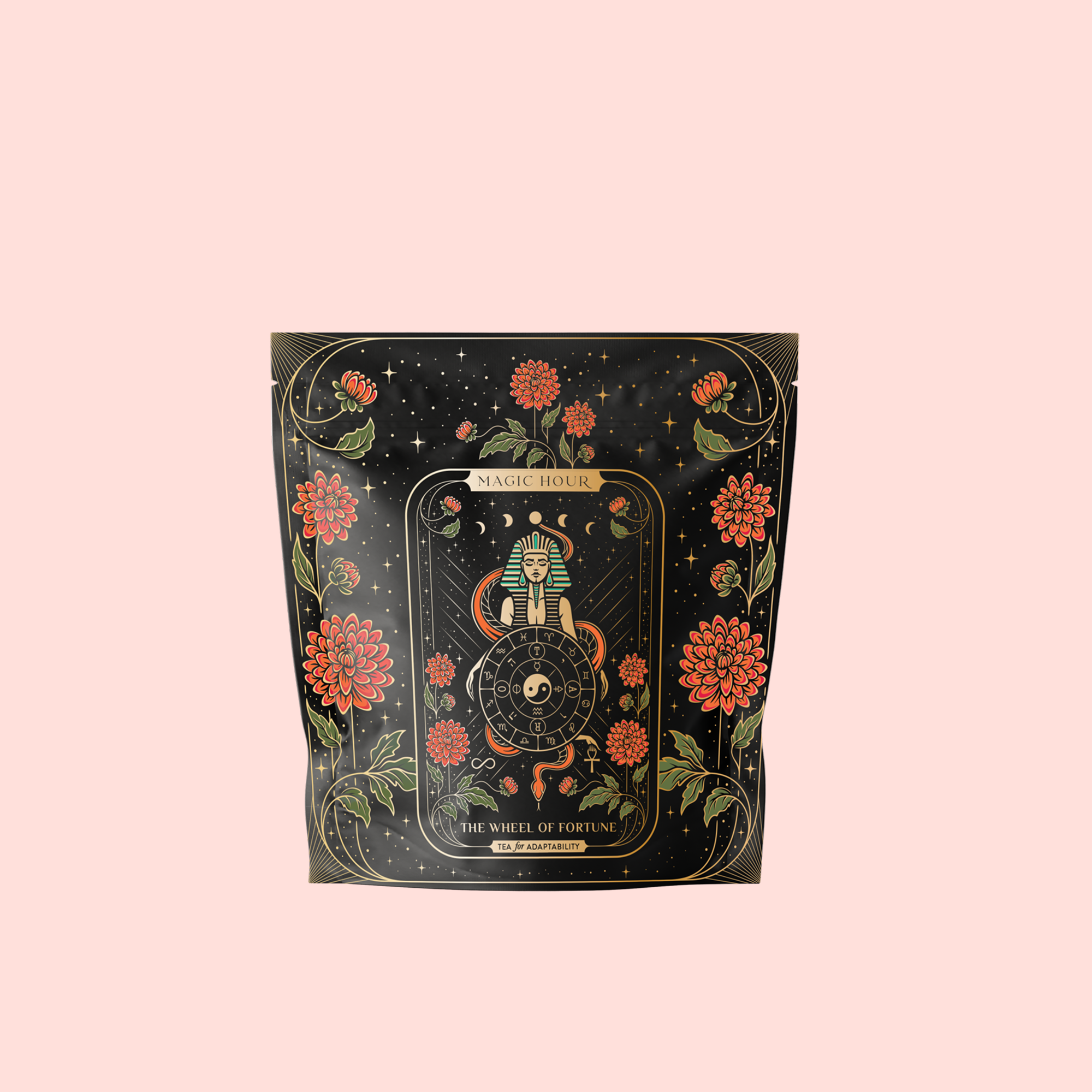 A black tea pouch with ornate floral and star designs, featuring "The Wheel of Fortune: Ginseng Spice Tea for Adapting to Change" by Magic Hour—a tarot-inspired adaptogenic wellness blend on a pale pink background.