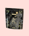 The Star: Vanilla-Ginger Beauty Potion with Jasmine & Shatavari is an organic herbal tea in a pouch featuring celestial gold and black artwork, stars, flowers, and leaves on a pale pink background.