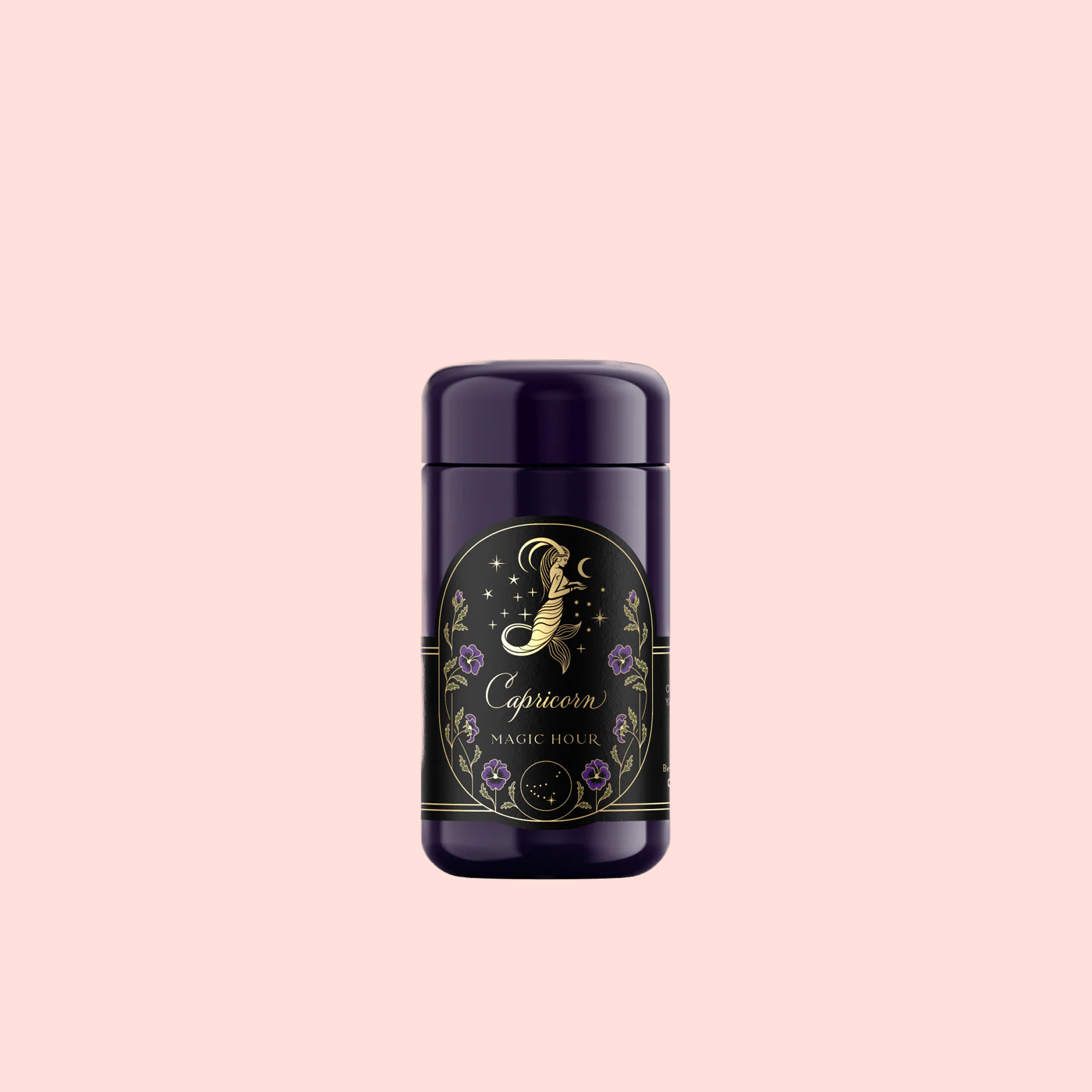 A dark purple cylindrical container with a gold and floral label reading “Capricorn: Maple Oolong Tea,” featuring a mystical Se Chung Oolong design, set against a pale pink background.
