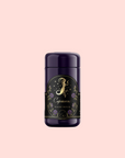 A dark purple cylindrical container with a gold and floral label reading “Capricorn: Maple Oolong Tea,” featuring a mystical Se Chung Oolong design, set against a pale pink background.
